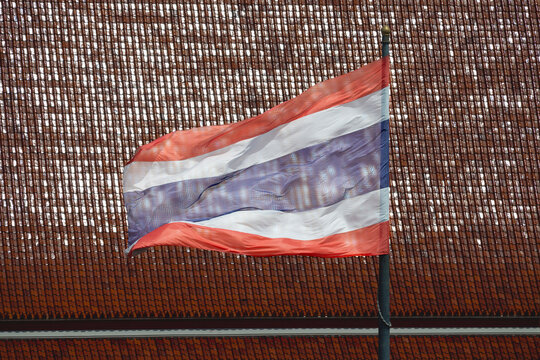 Thai flag waving in the wind against a tiled roof background