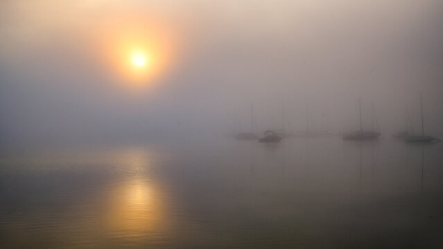 Foggy sunrise over boats in Lake Starnberg harbor at Seeshaupt Bavaria