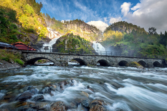 Waterfall and arched stone bridge over river in Fjord Norway