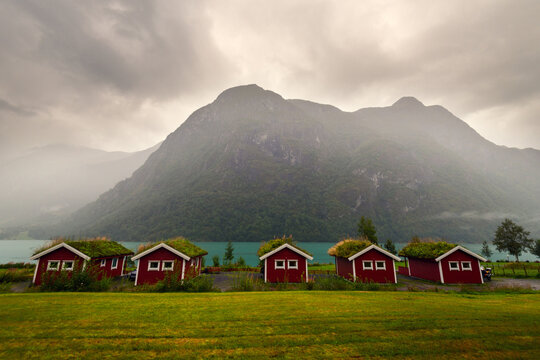Row of red wooden huts with grass roofs near Oldevatnet lake in Norway