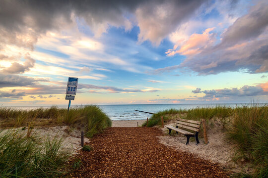 Beach path with wooden bench and sand dunes at Baltic Sea sunset