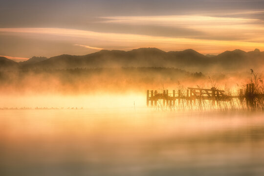 Morning mist over Starnberger See lake with dock in Bavaria Germany