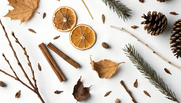Autumn and Winter Flat Lay with Maple Leaves, Cinnamon, Dried Orange Slices, and Pine on White
