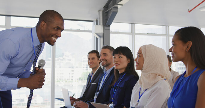 African American businessman passionately addresses a diverse audience at a seminar.