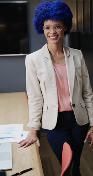 Portrait of happy casual businesswoman with blue afro in office