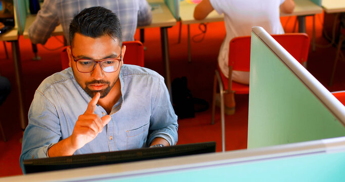 Portrait of businessman in glasses using computer, unaltered