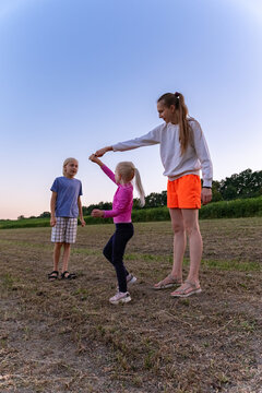 Mother and children laughing and playing together in a sunny summer field, carefree outdoor bonding and joyful family moments creating lasting memories