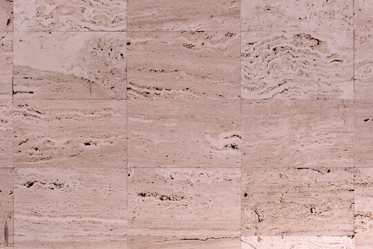 Travertine tiles creating a textured wall surface, showcasing natural porous patterns and warm earthy tones suitable for architectural or design backgrounds