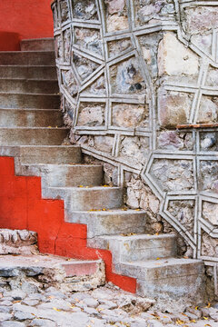 Stone steps with red painted edges beside stone masonry wall, mexico