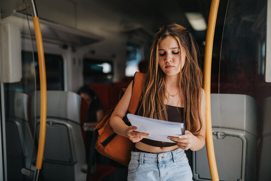 Student reads study notes while commuting on a train, combining education, learning and public transportation during travel.
