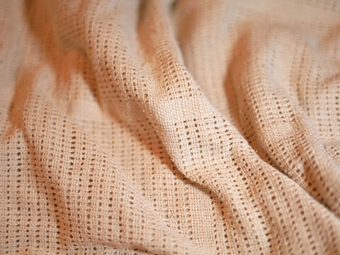 Peach fabric gathers in soft folds, showing an open texture and drape central to textile design, with a patterned surface that informs fabric selection for sewing projects and decorative furnishings.