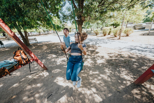 Student swings at an outdoor playground, enjoying friendship, recreation and carefree fun during a campus break.