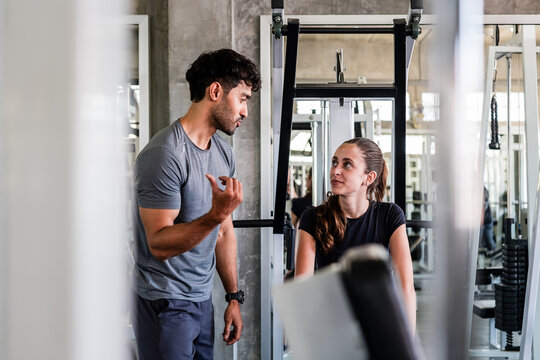Trainer talks with a woman beside gym equipment
