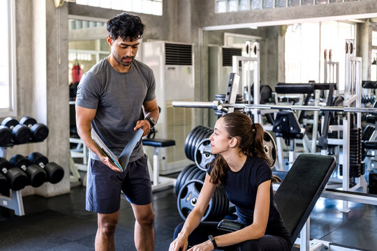 Trainer reviews a workout plan with a woman at the gym
