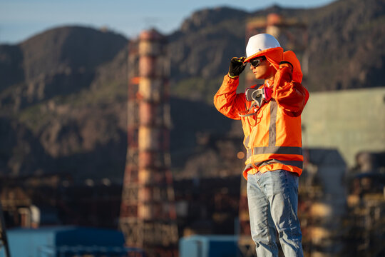 Mining worker adjusting his safety helmet near an industrial plant in northern Chile