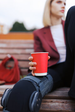 Woman Sitting on Bench With a Red Cup in Hand in the Park