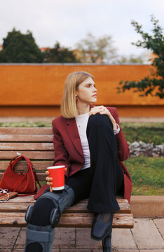 Woman Sitting on a Bench in the Park With a Drink