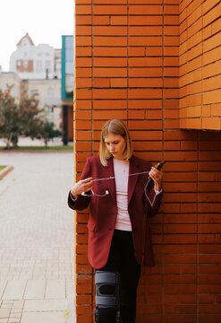 Woman Standing by a Brick Wall While Using Her Phone Outdoors