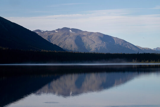 Mountain above a lake with reflection in the water on a sunny summer day in Alaska.