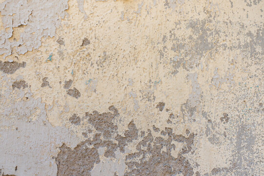 Aged gray cement wall with chipped white and yellow paint, multiple cracks and distressed grunge surface