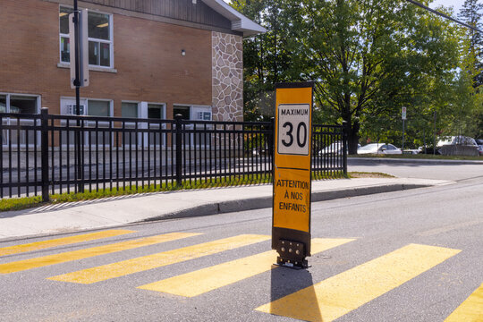 School zone crosswalk and maximum 30 speed sign warning drivers to watch for children beside a fenced school. Val-David Quebec