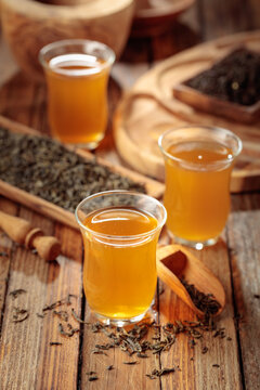 Freshly brewed green tea and dried tea leaves on an old wooden table.