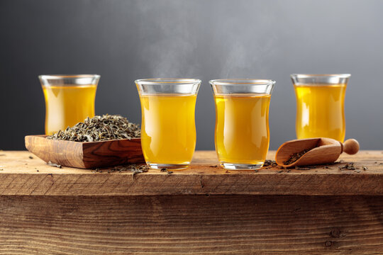 Green tea in small glass cups on an old wooden table.