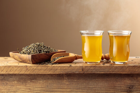Green tea in small glass cups on an old wooden table.