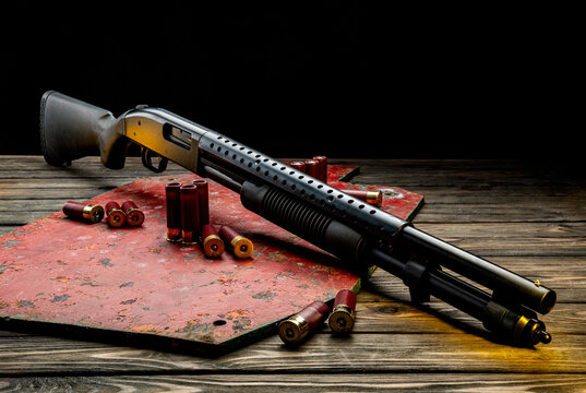 Pump-action shotgun with red shells on a rustic wooden and metal back