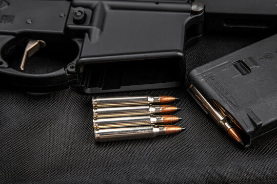 Rifle bullets, magazine, and firearm receiver on dark fabric back
