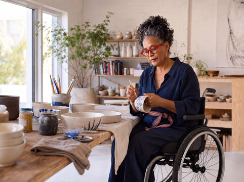 Mature black woman in wheelchair creating ceramic art in her studio