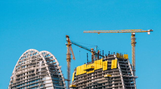 Modern Urban Skyscraper Construction with Tower Cranes, Curved Architecture and City Skyline.