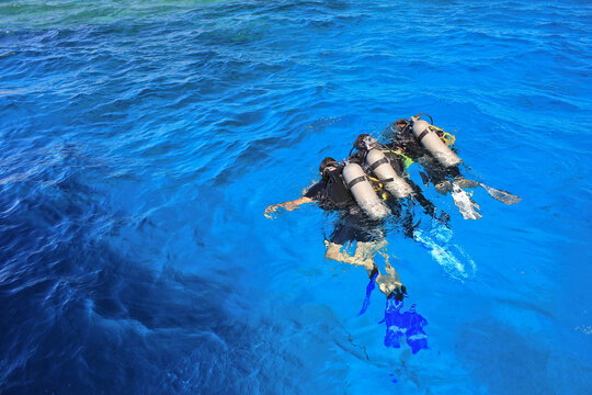 Group of professional divers with equipment training in transparent aquamarine sea during safari tour in Egypt