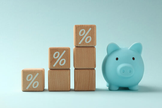 Wooden cubes with percents signs and piggy bank on light blue background. Discount concept