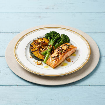 rilled salmon dish with broccoli, roasted squash, nuts, and seeds on a blue wooden table