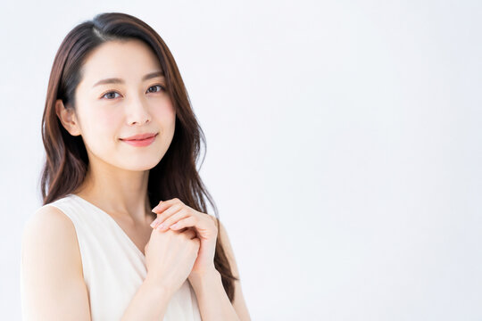 胸元で手を組み微笑む白い服の女性