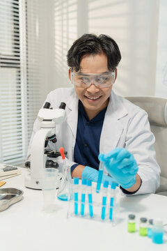 Asian male scientist using micropipette for chemical experiment with microscope in laboratory
