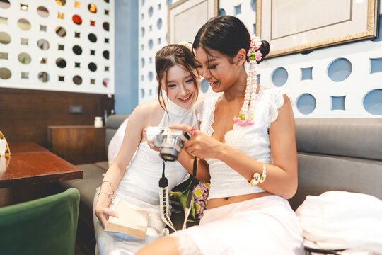 Two young asian women using digital camera at Thai food in authentic restaurant