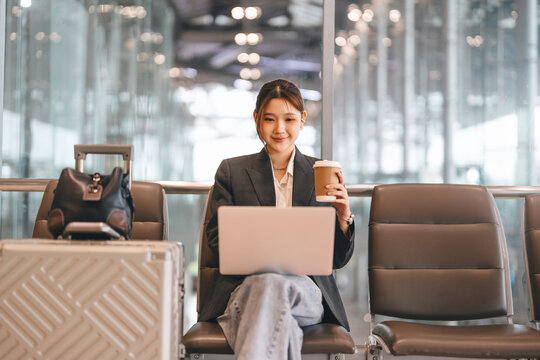 Young adult asian business woman using laptop video conference meeting online at international airport terminal
