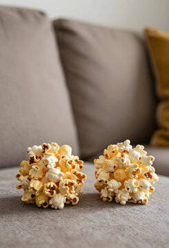 Movie night entertainment and leisure, two popcorn balls on a soft couch for home relaxation and snack time with friends or family in a cozy setting