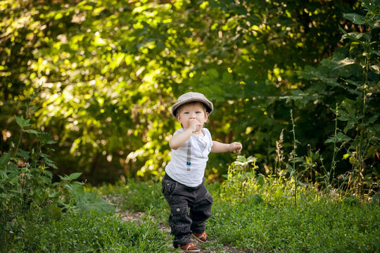 Cute little boy in vintage outfit with suitcase sitting in the park