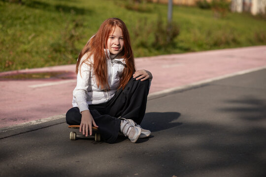 Little Redhead Girl Riding Skateboard In Autumn Park
