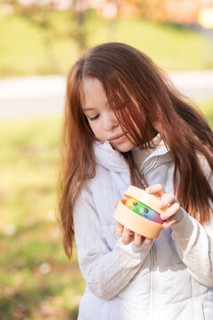 Cute girl holding a colorful dumpling squishy toy outdoors