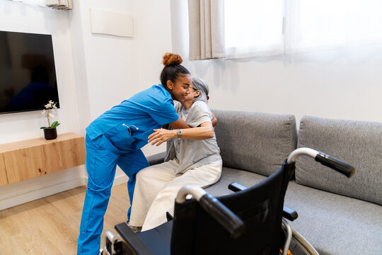 Latina home health nurse embracing an elderly woman at home, offering compassionate support beside her wheelchair