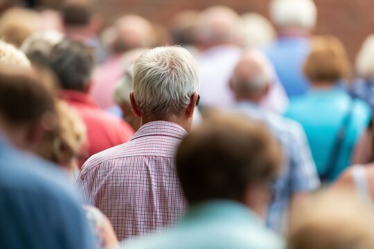 Senior man standing in crowd, people gathered outdoors