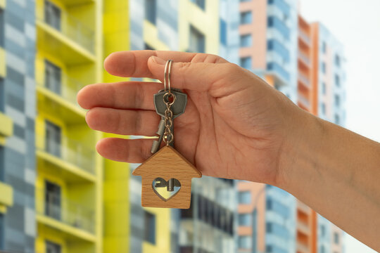 Real estate purchase or rental. Female hand holding apartment keys outdoors.