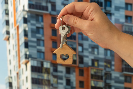 Buying or renting real estate, moving to new apartment. Hand holding keys outdoors.