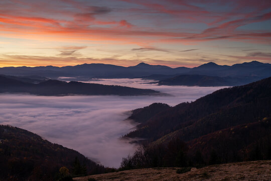 Highland sunrise over peaks and low clouds in valley