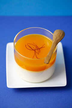 Yogurt dessert topped with saffron threads in a glass cup
