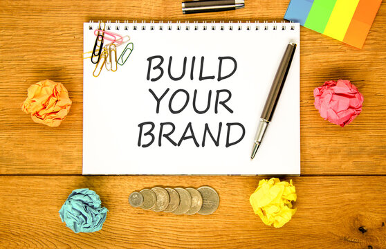 Build your brand words symbol. Concept words Build your brand on beautiful white note. Beautiful wooden background. Colored paper. Business and build your brand concept. Copy space.